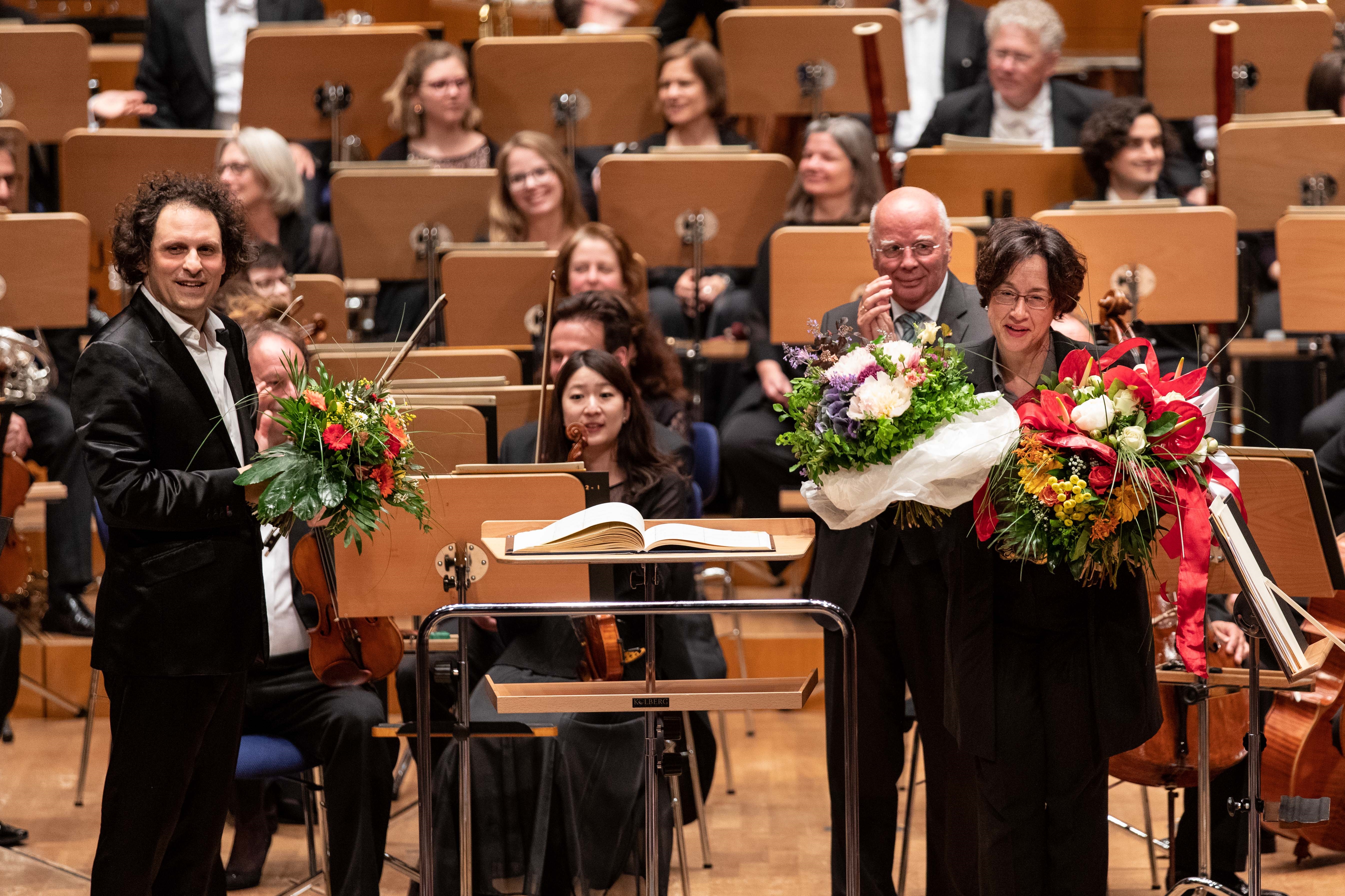 Abschied von Marieddy Rossetto auf dem Podium der Tonhalle Düsseldorf nach dem Konzert vom 3.6.2019. Bild: Alexandre Bloch mit Marieddy Rossetto. Musikvereinsvorsitzender Manfred Hill nach der Blumenübergabe und die Düsseldorfer Symphoniker im Hintergrund - Danke ! Marieddy Rossetto (Foto: Susanne Diesner)