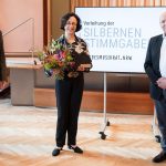 Verleihung der Silbernen Stimmgabel des Landesmusikrats 2021 an Marieddy Rossetto (Mitte) durch Holger Müller (links); die Laudatio hielt Rolf Kessler (rechts) ©vlago