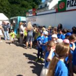 Kinder der Ferdinand-Heye-Schule und der GGS Knittkuhl warten im heißen Sonnenlicht auf ihren Auftritt