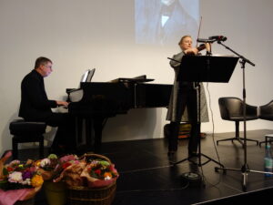 20.10.2025: Die Sängerin Rosi Dasch spricht über ihre Lieder aus dem Ghetto von Vilnius und trägt diese mit Gesang und Geige, begleitet am Klavier von Robert Boden eindrucksvoll vor