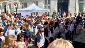 14.6.2025 Art:walk Veranstaltung auf der Bilker Straße, der Straße der "Romantik und Revolution" zwischen Heinrich-Heine-Institut und Schumannhaus. SingPause-Kinder von drei Schulen treffen sich spontan vor der Bühne und singen begeistert mit ihren Singleiterinnen Maria Carreras und Clementine Schwander und mit Singleiter Martin Lucaß. Hier im Bild Kinder der Sternwartschule Düsseldorf. Ein toller Auftritt mit begeisterten Zuhörerinnen und Zuhörern. Unter dem Zelt in Rot die Direktorin des Heinrich-Heine-Instituts Frau Dr. Sabine Brenner-Wilczek