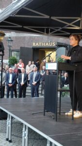 7.10.2026-18.00 Uhr: Bewegendes Gedenken an den Hamas-Terror vom 7.10.2023 - 6.29 Uhr - mit über 40 Organisationen aus der Stadtgesellschaft vor dem Rathaus und an der Treppe am Burgplatz. Die stellvertretende Ministerpräsidentin des Landes NRW, Frau Ministerin Mona Neubaur, bei ihrer sehr persönlichen und bewegenden Rede auf dem Tathausvorplatz.
